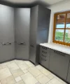Eine moderne, graue Küche mit Eckschränken und einem Fenster, Nolte Küchen.