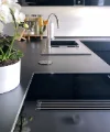 Een moderne keuken met zwart werkblad en witte orchideeën, Nolte Kitchen.