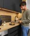 Ein Mann bereitet Kaffee in einer modernen Küche von Nolte Küchen zu.