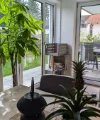 Een woonkamer met grote ramen, planten en een tafel. Nolte Living.