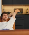 Ein Mann entspannt auf einem Sofa vor einer modernen Küchenzeile von Nolte Küchen.