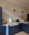 Eine moderne Küche mit blauen Schränken und goldenen Akzenten, beleuchtet durch Sonnenlicht. Nolte Küchen.