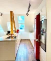 Eine moderne Küche mit roten Akzenten und Holzelementen, beleuchtet durch Dachfenster. Nolte Küchen.