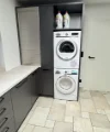 Ein Hauswirtschaftsraum mit Waschmaschine und Trockner in modernen Schränken von Nolte Hauswirtschaftsräume.