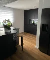 Een moderne keuken met donkere kasten en houten vloer van Nolte Kitchen.