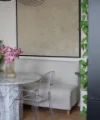 Ein eleganter Essbereich mit Marmortisch, Blumen und transparenten Stühlen, eingerahmt von Pflanzen. Nolte Living.