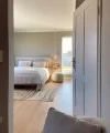 Ein modernes Schlafzimmer mit Doppelbett und Teppich, durch eine geöffnete Tür gesehen. Nolte Living.