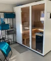 Eine moderne Sauna im Raum mit einem blauen Liegestuhl und Regalen, Teil von Nolte SPA.