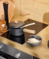 In einer modernen Küche mit Holzdetails steht ein Herd mit Topf und Reisschüssel. Nolte Küchen.