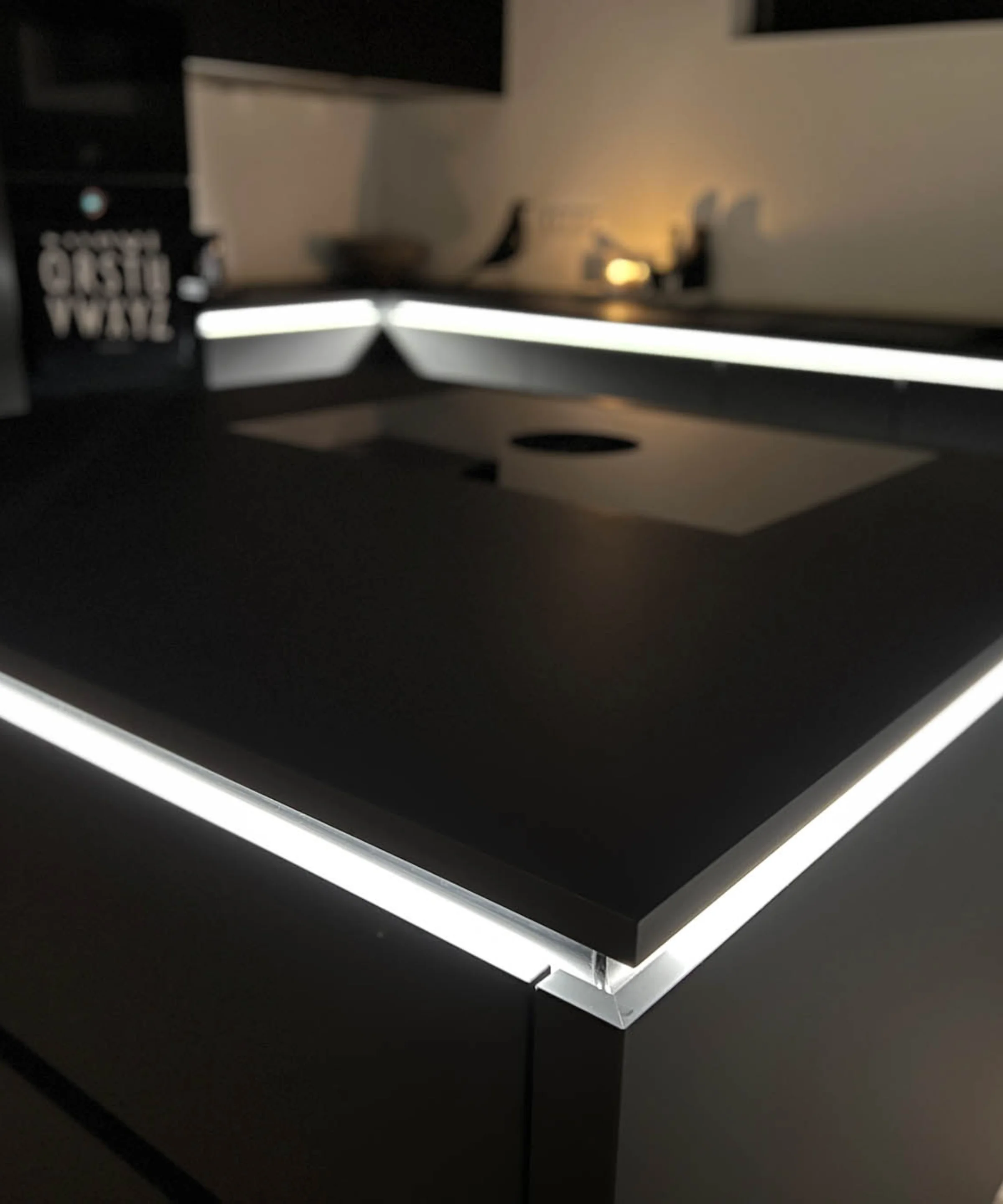 Eine moderne, schwarze Küche mit beleuchteter Insel, entworfen von Nolte Küchen.