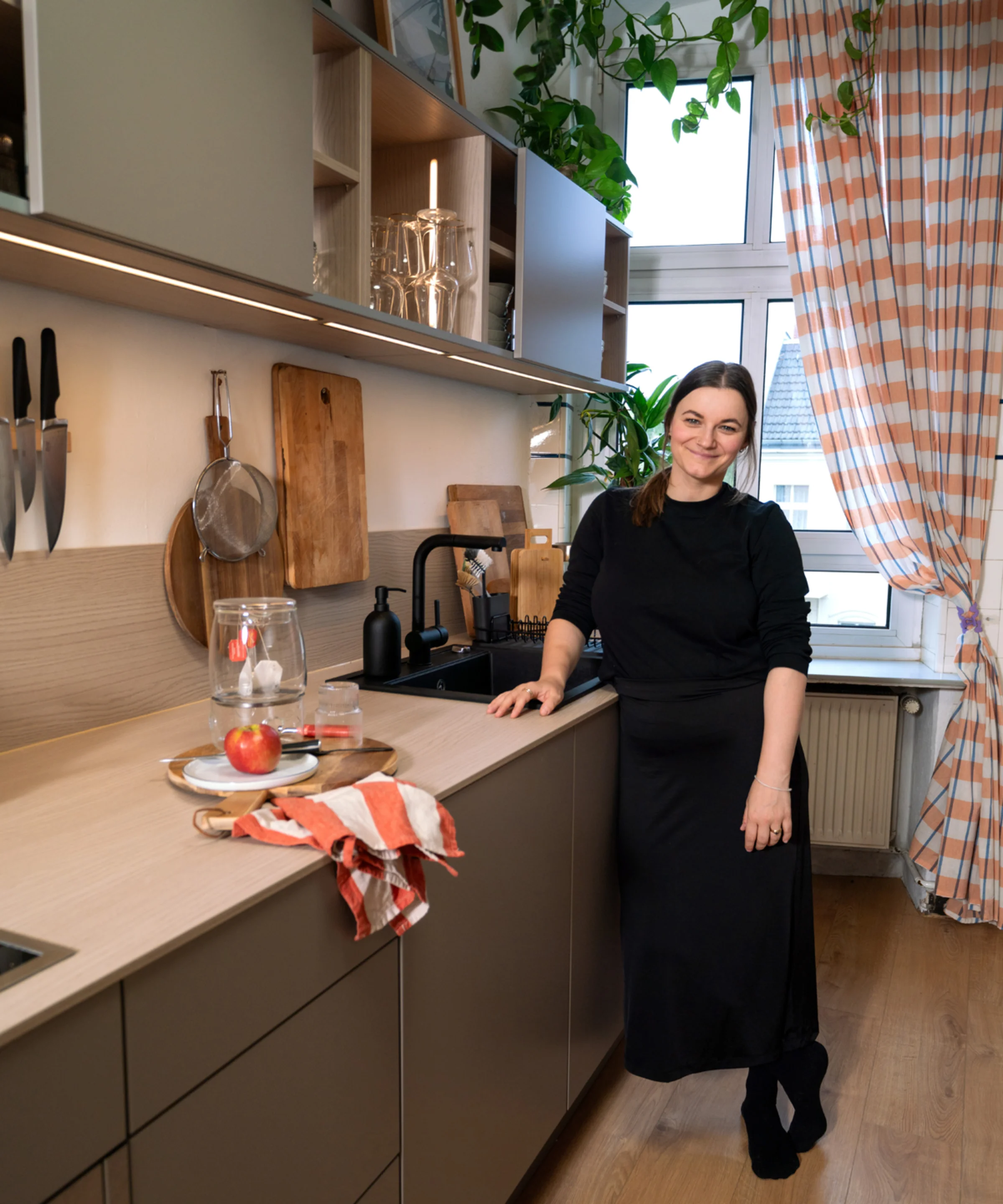 In der modernen Nolte Küchen steht eine Frau an der Arbeitsplatte mit Holzbrett und Gläsern.