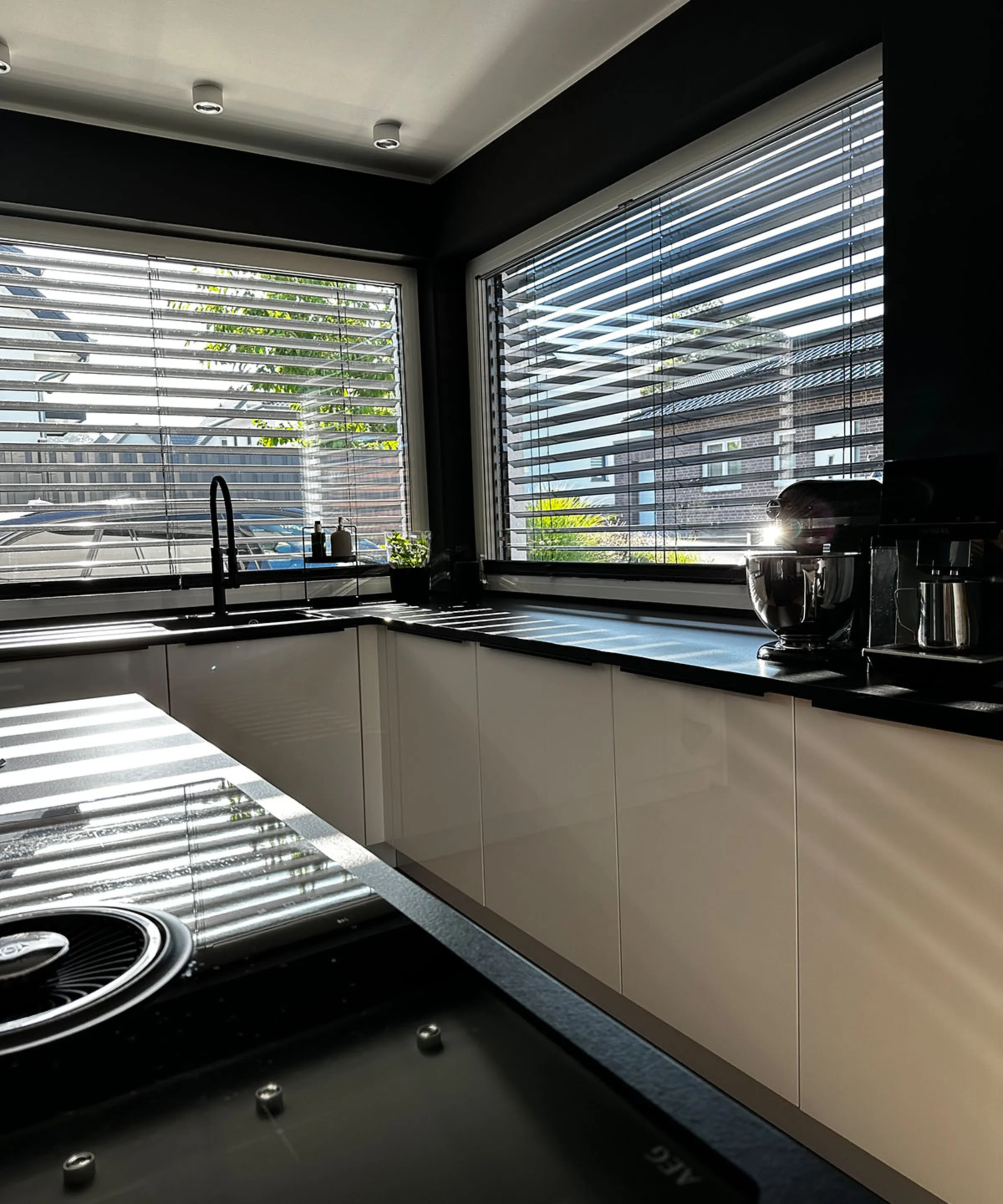 Eine moderne Küche mit weißen Schränken und großen Fenstern, die viel Licht hereinlassen. Nolte Küchen.