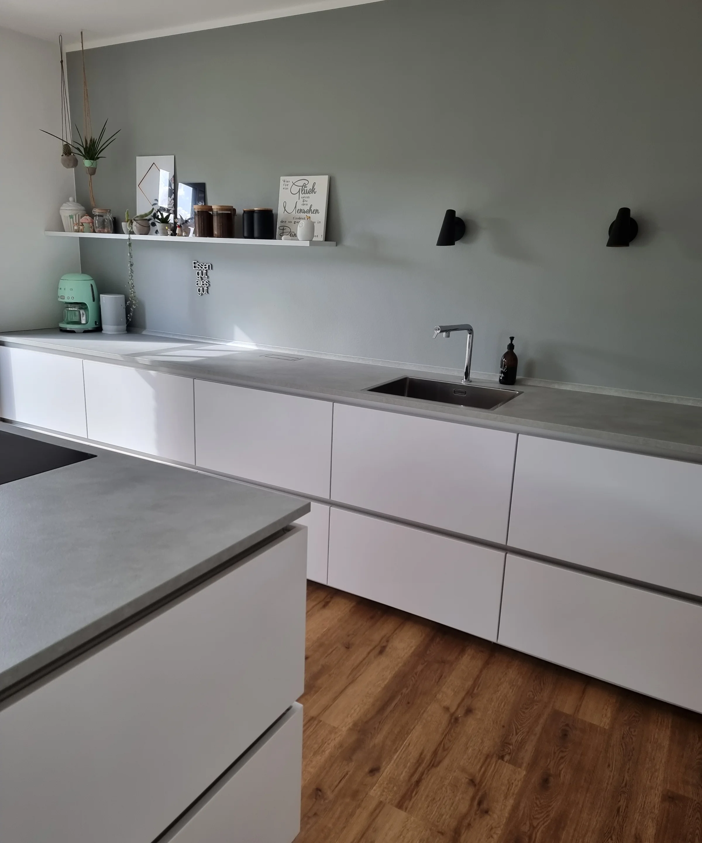 Een moderne keuken met witte kasten en houten vloer, gepresenteerd door Nolte Kitchen.