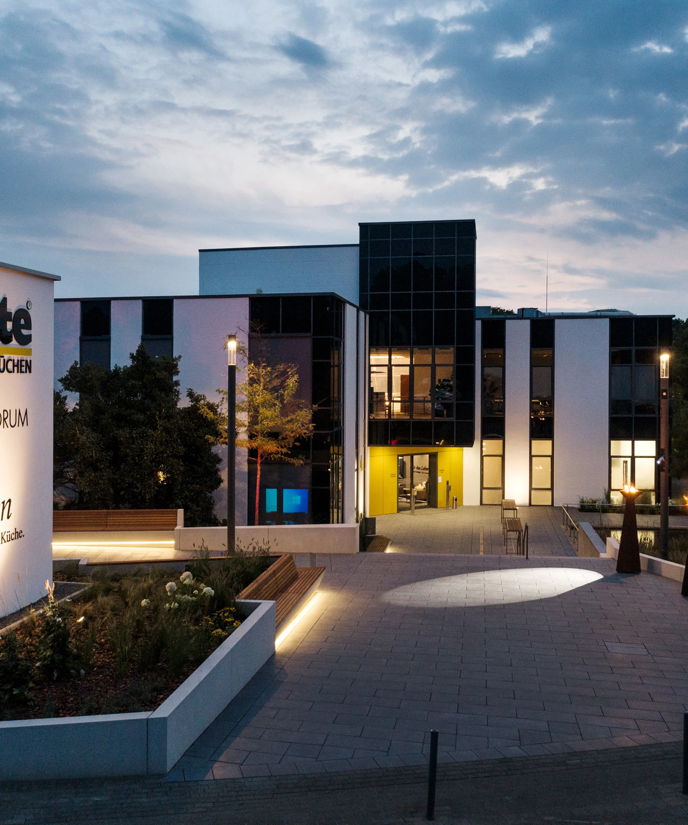 The modern Nolte Forum building at dusk, surrounded by lit pathways and green spaces.