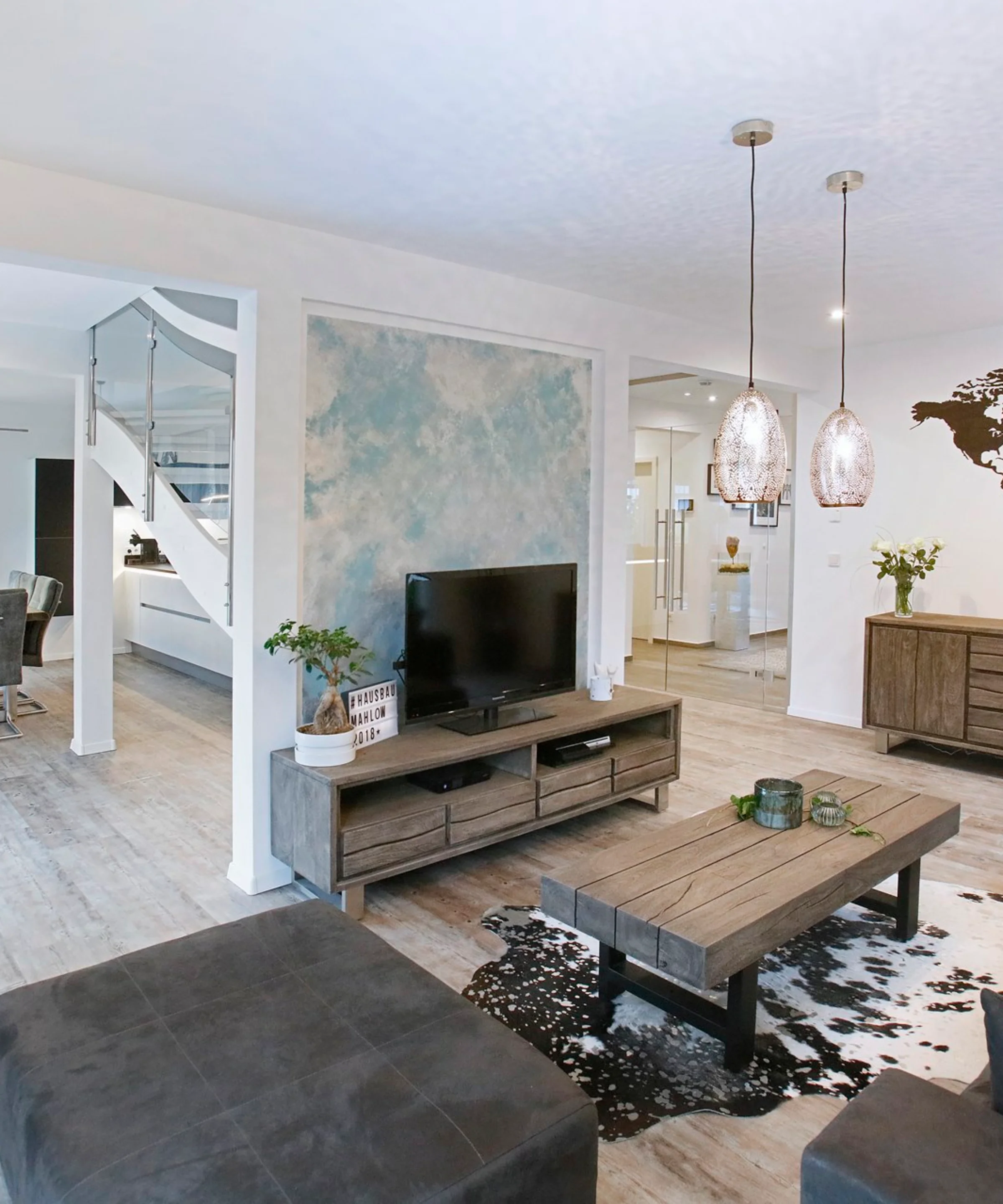 Ein modernes Wohnzimmer mit Holzmöbeln und Weltkarten-Dekor an der Wand, Nolte Living.