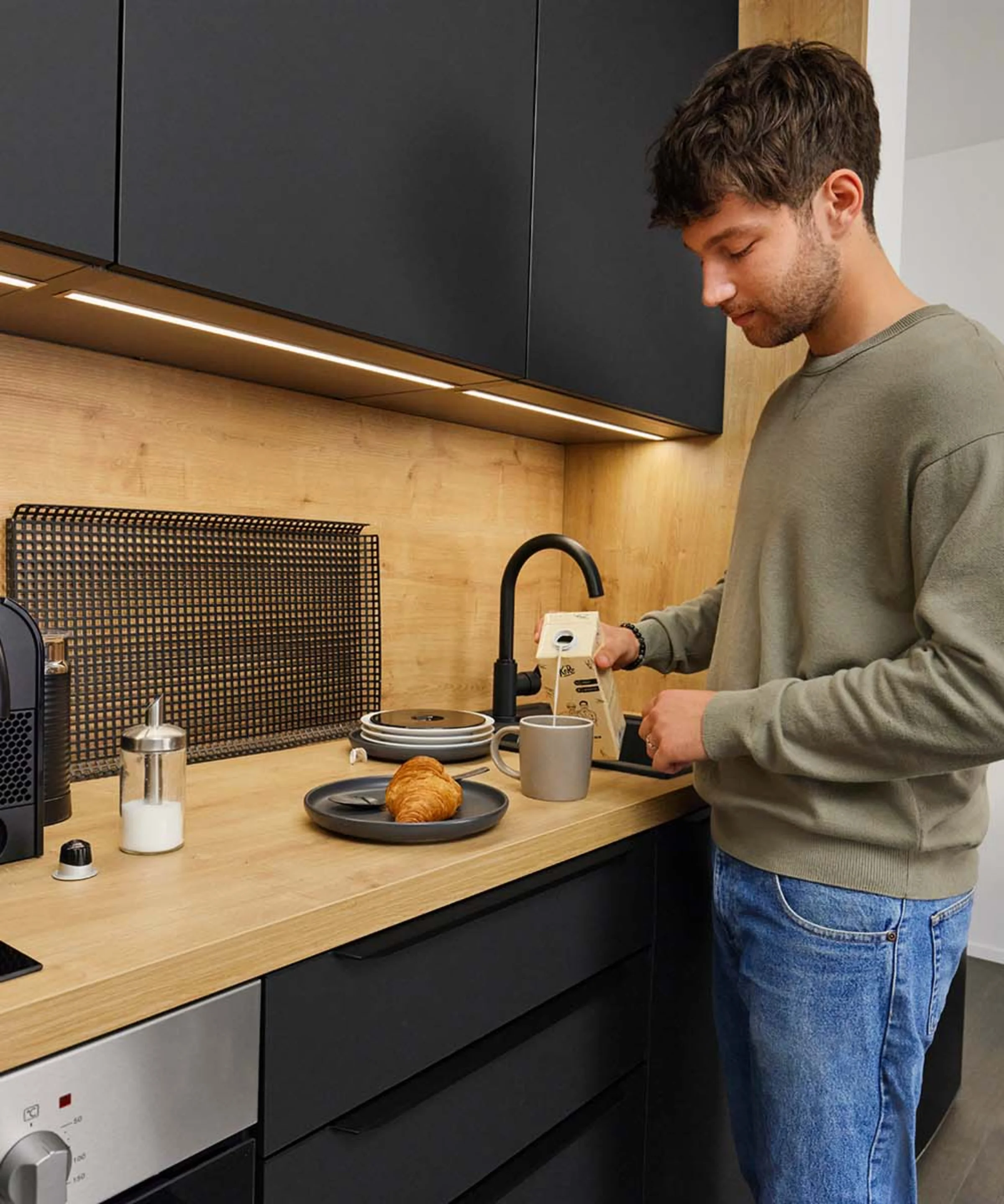 Ein Mann bereitet Kaffee in einer modernen Küche von Nolte Küchen zu.