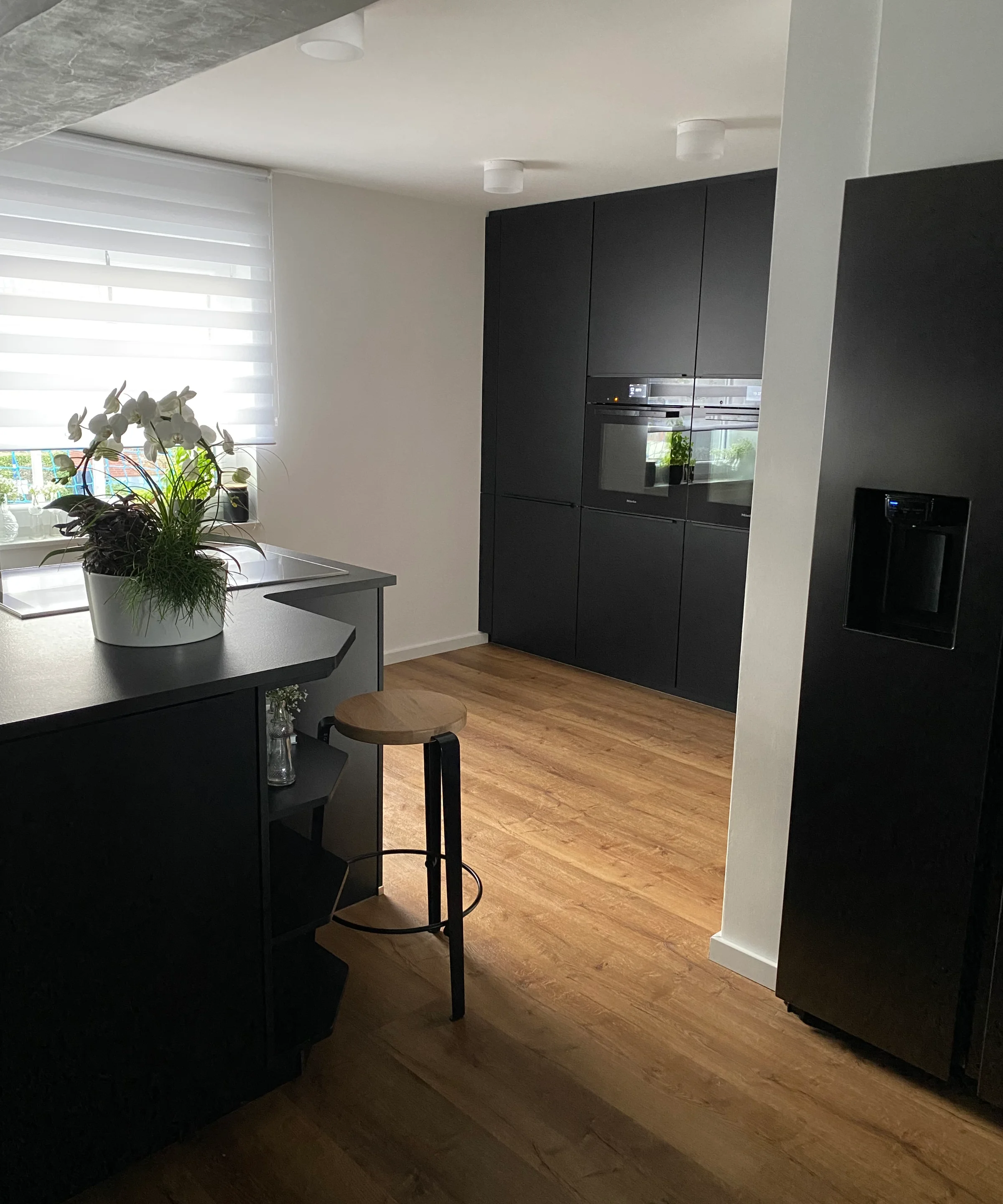 Eine moderne Küche mit dunklen Schränken und Holzfußboden von Nolte Küchen.