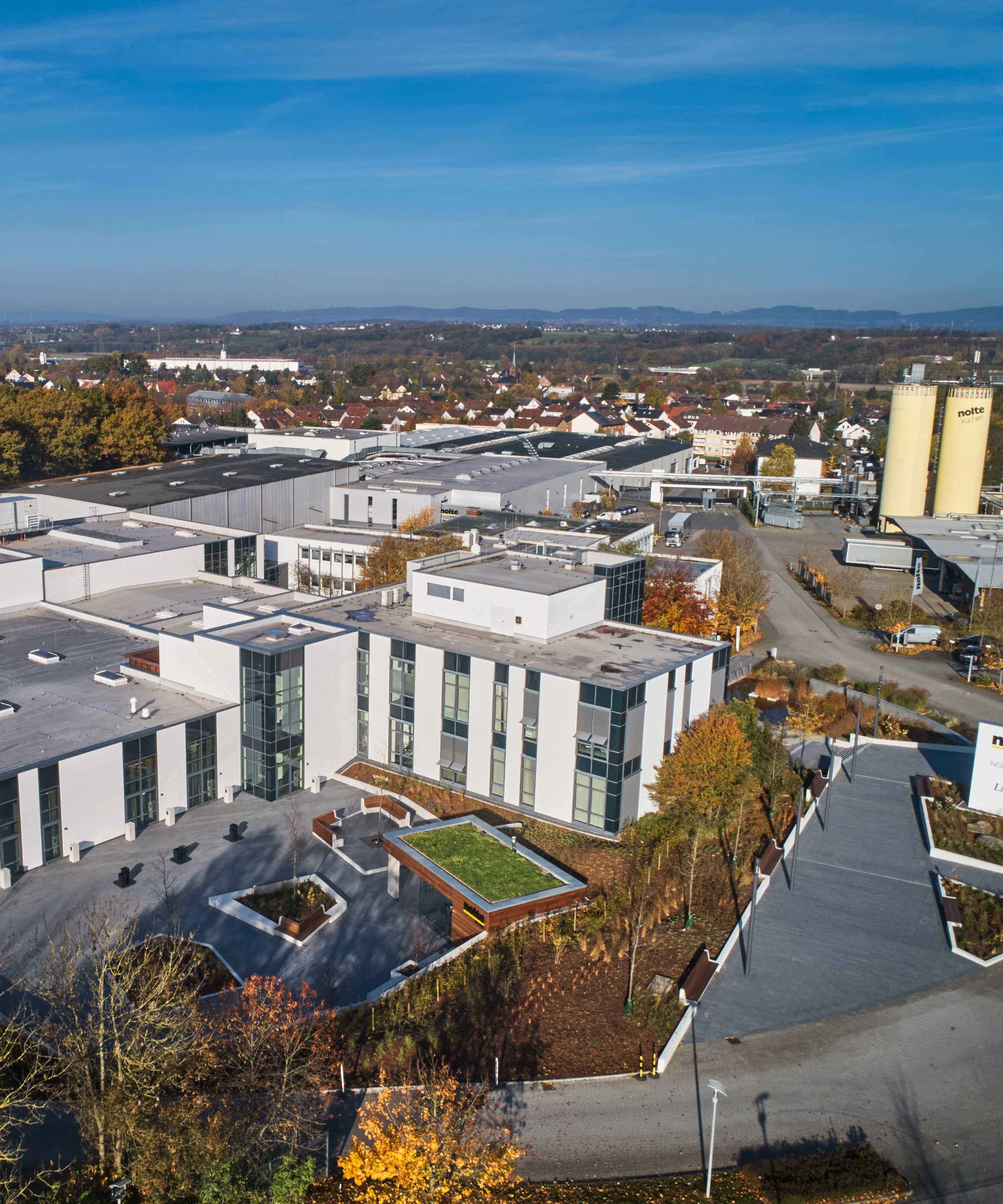 A modern building with large glass fronts surrounded by an autumn landscape. Nolte Kitchens.