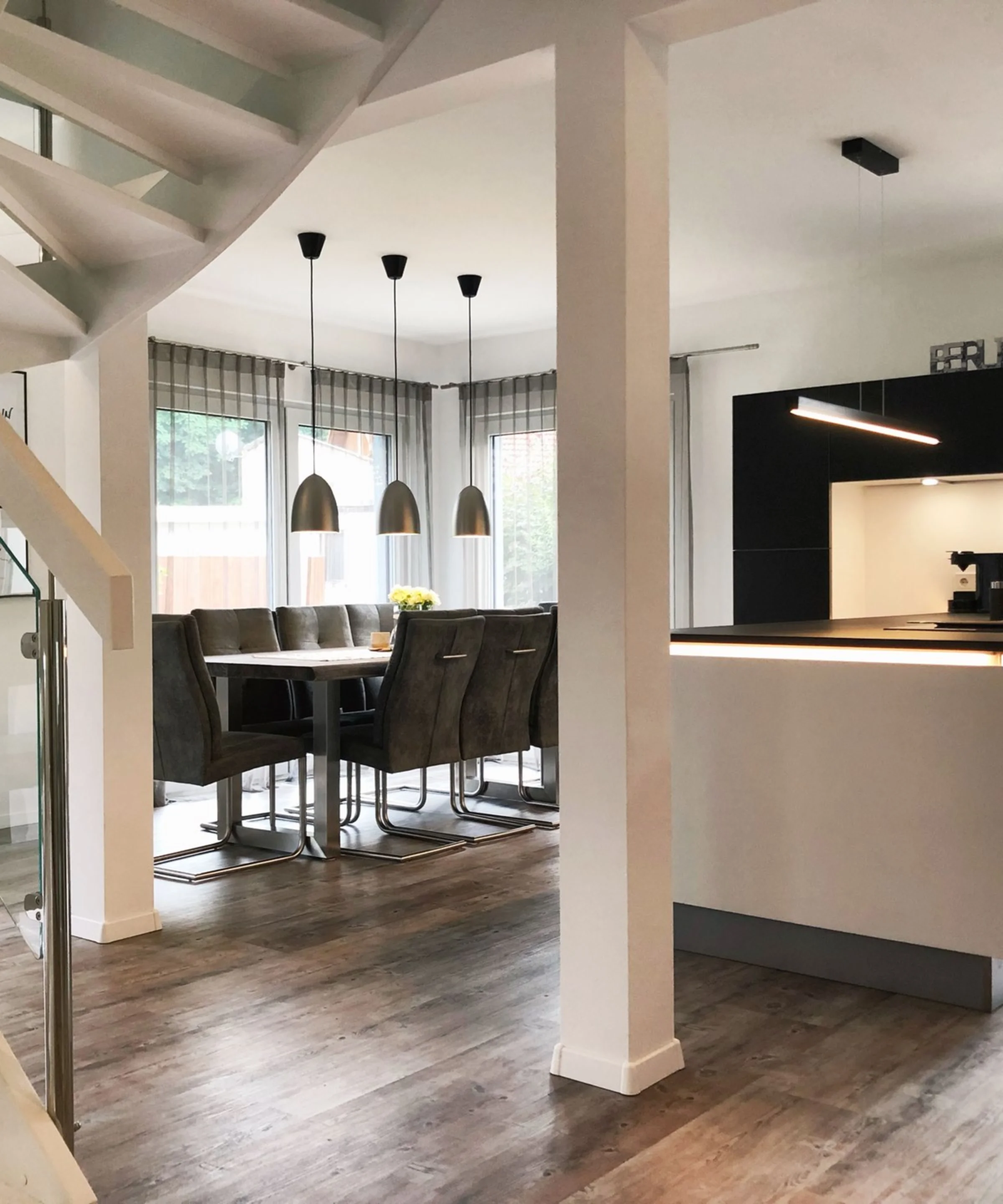 Eine moderne Nolte Küchen Einbauküche mit Essbereich und Treppe in einem offenen Wohnraum.