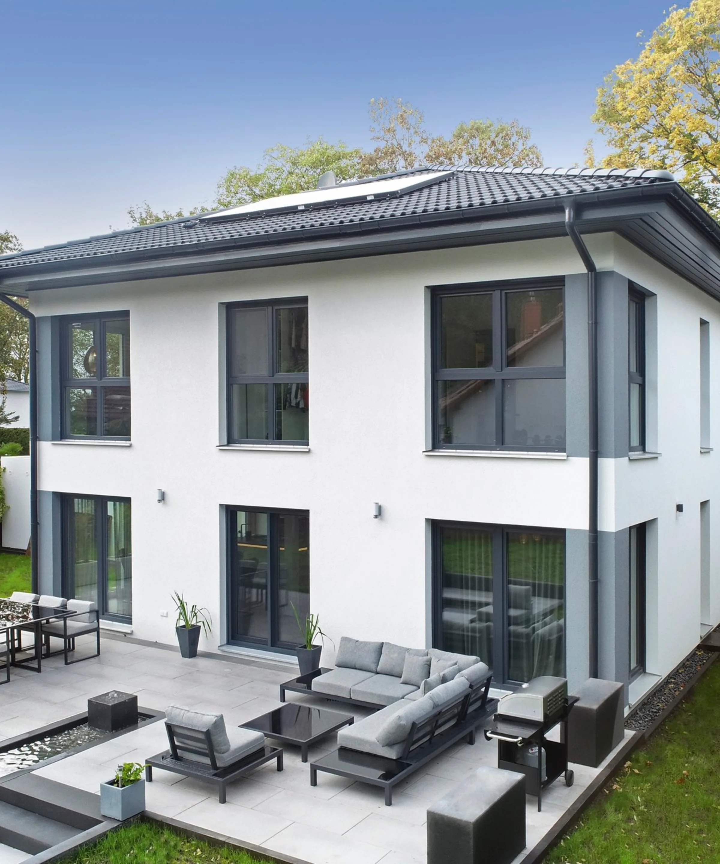 Ein modernes, zweistöckiges Haus mit Terrasse und Garten ist zu sehen.
