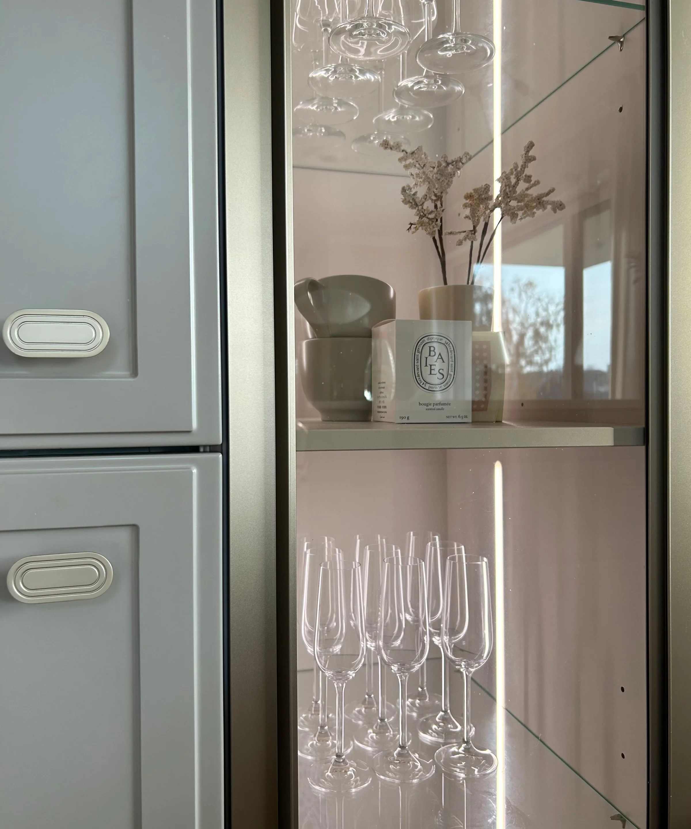 A glass display cabinet with wine glasses and decor in a kitchen, Nolte Kitchen.