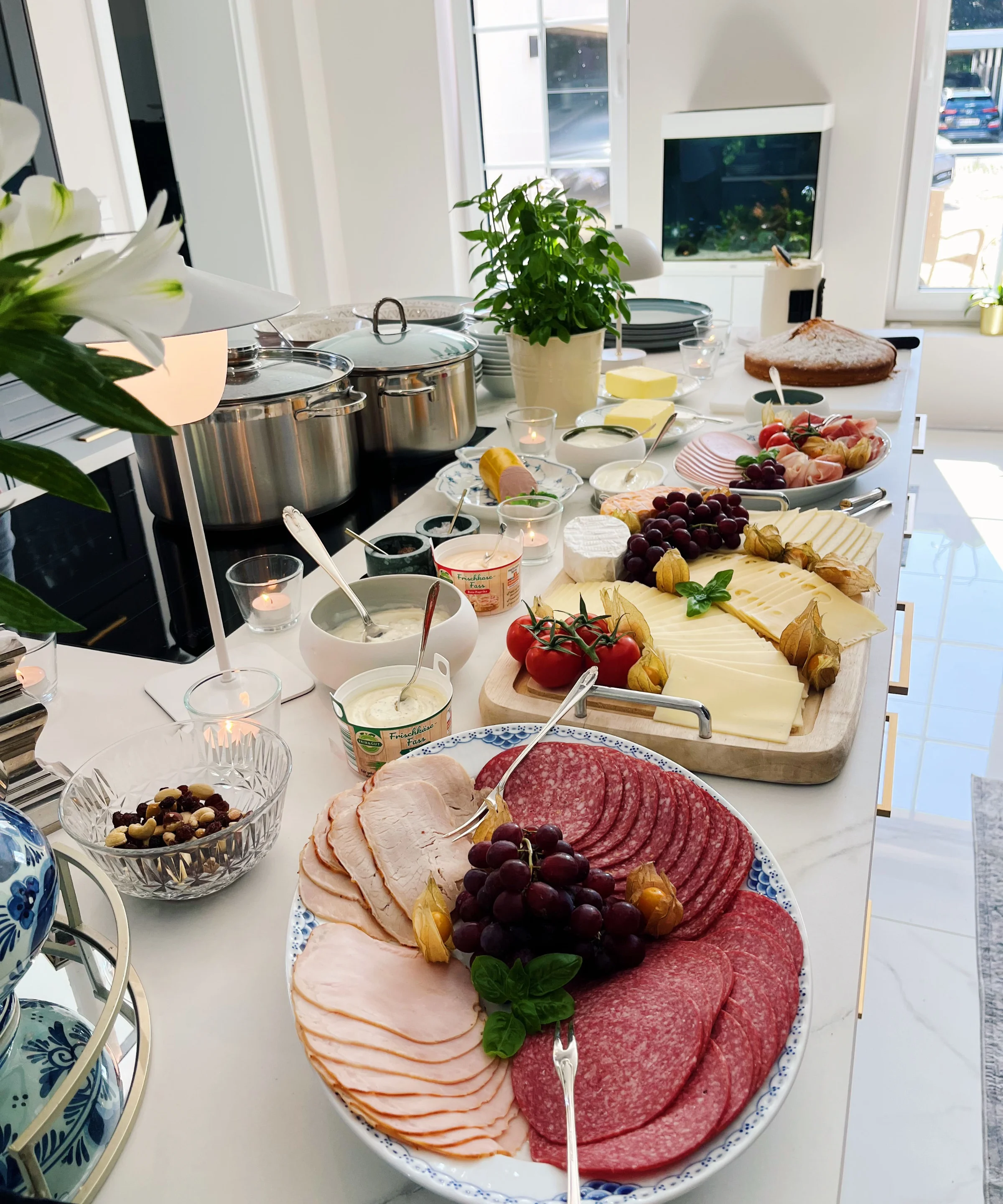 Ein reich gedeckter Frühstückstisch in einer modernen Küche mit Aufschnitt und Käse, gestaltet von Nolte Küchen.