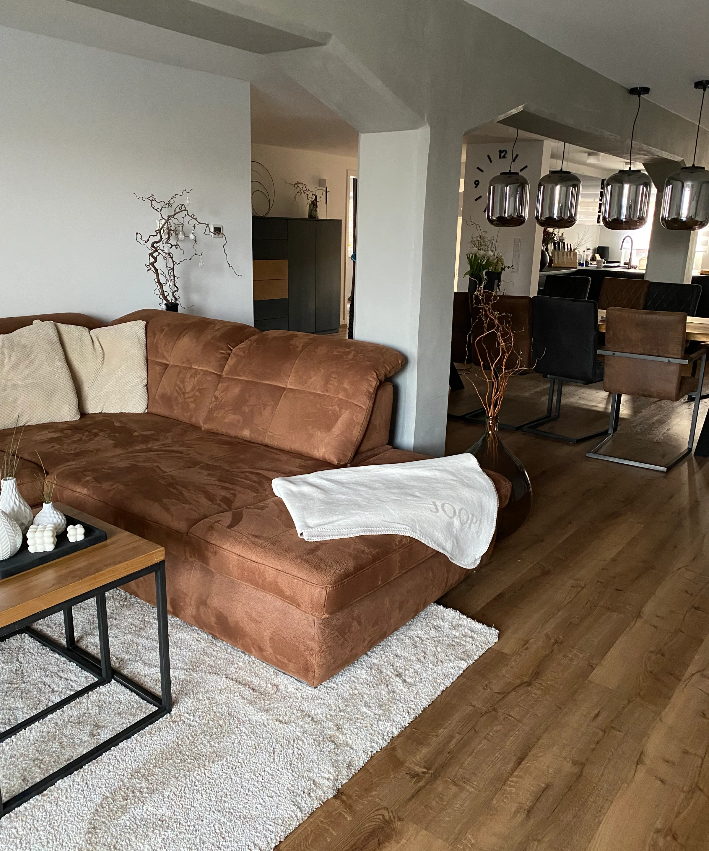 Een modern woonkamer met een bruine bank en eetgedeelte; Nolte Living.