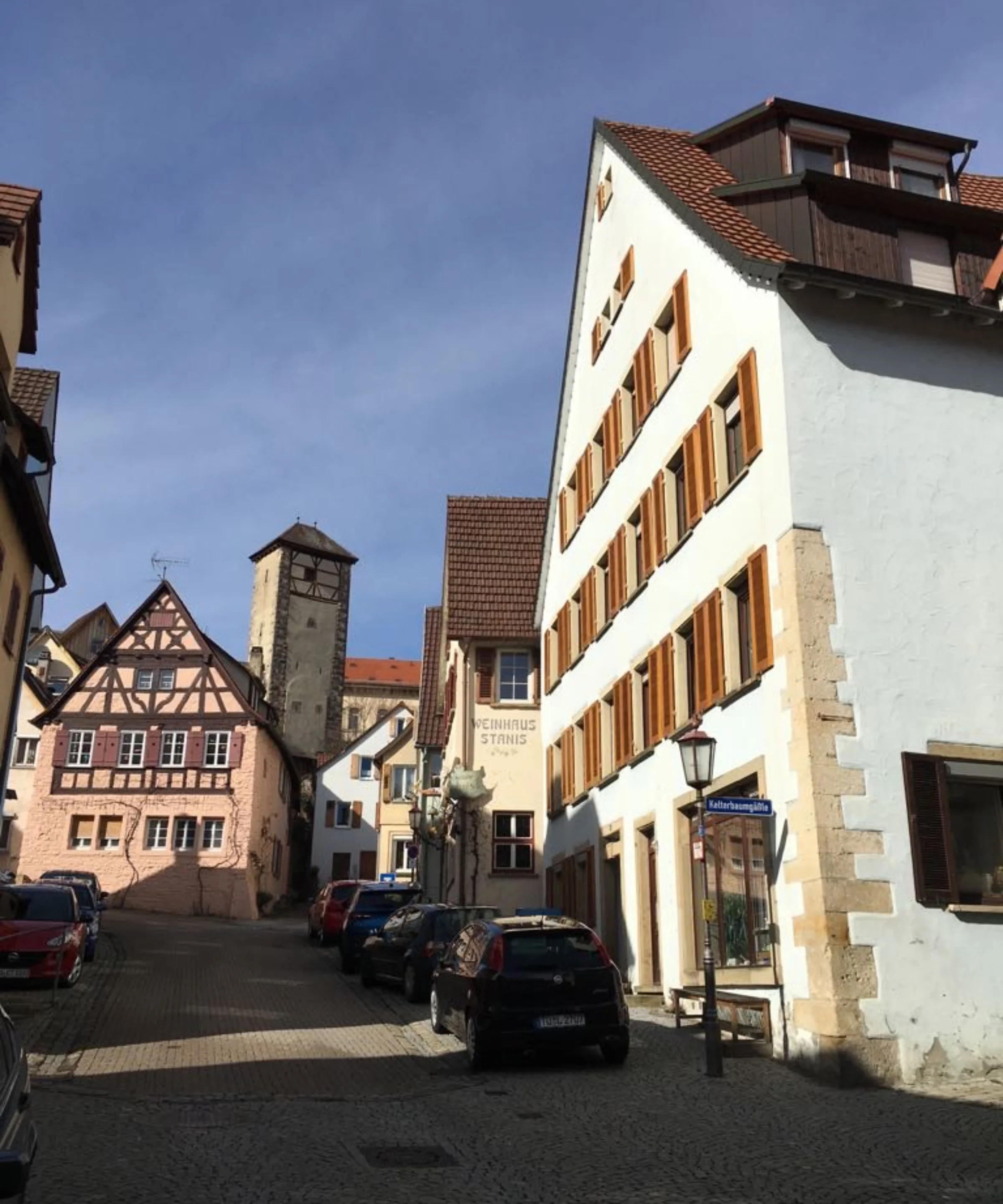 Eine malerische Altstadtstraße mit Fachwerkhäusern und einem Kirchturm im Hintergrund.
