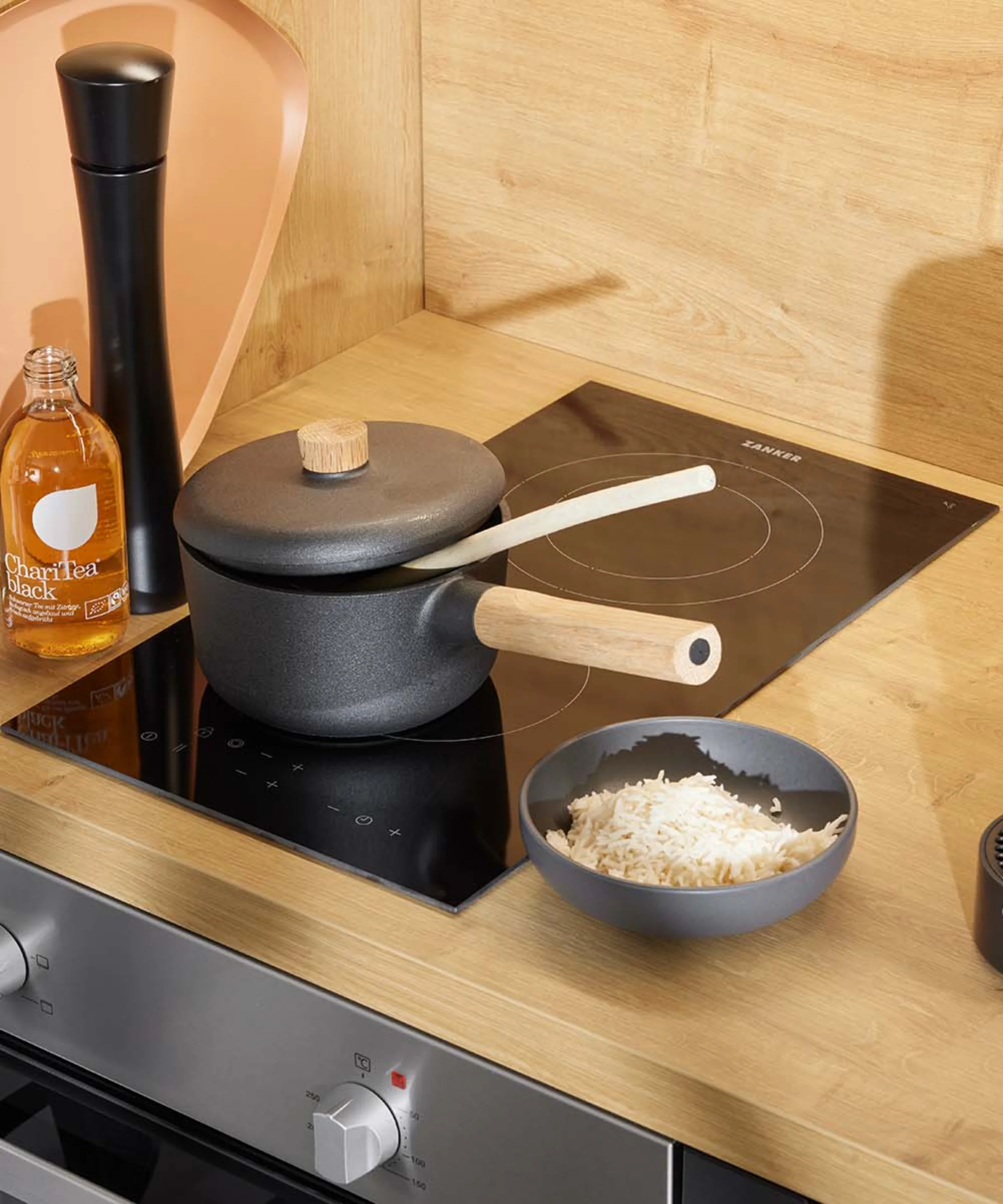 In einer modernen Küche mit Holzdetails steht ein Herd mit Topf und Reisschüssel. Nolte Küchen.