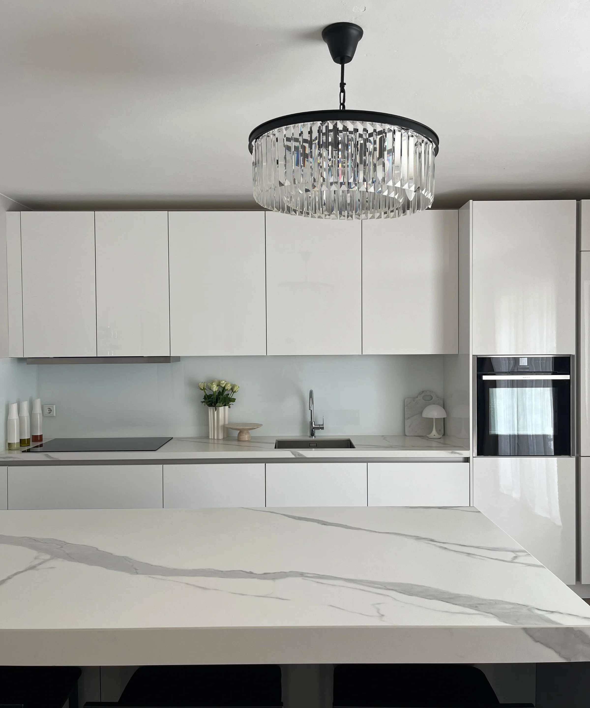 Eine moderne Küche mit weißem Interieur und Kronleuchter, gestaltet von Nolte Küchen.