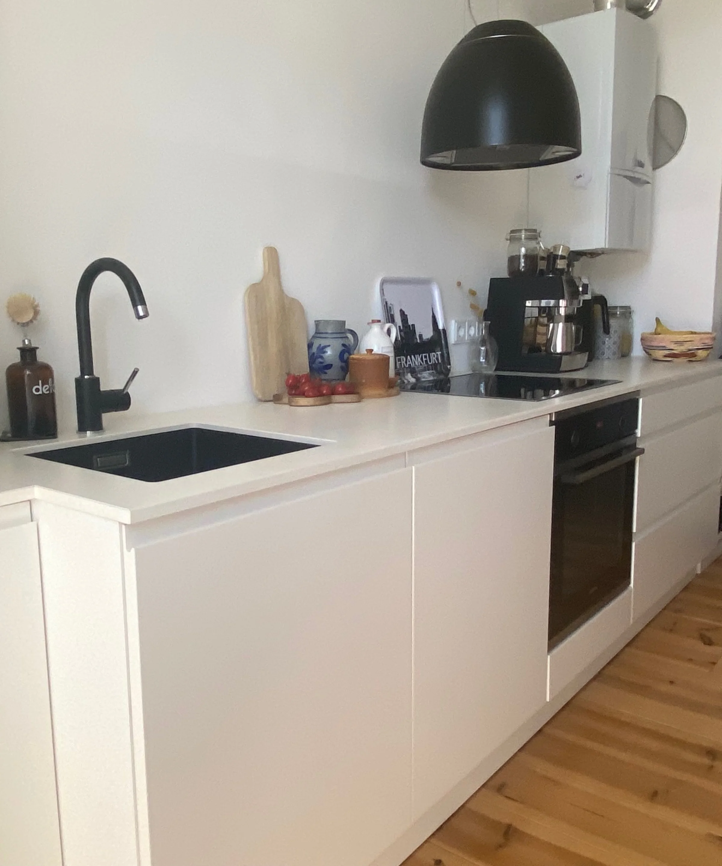 In einer modernen Küche mit weißen Schränken und Holzfußboden ist Nolte Küchen zu sehen.