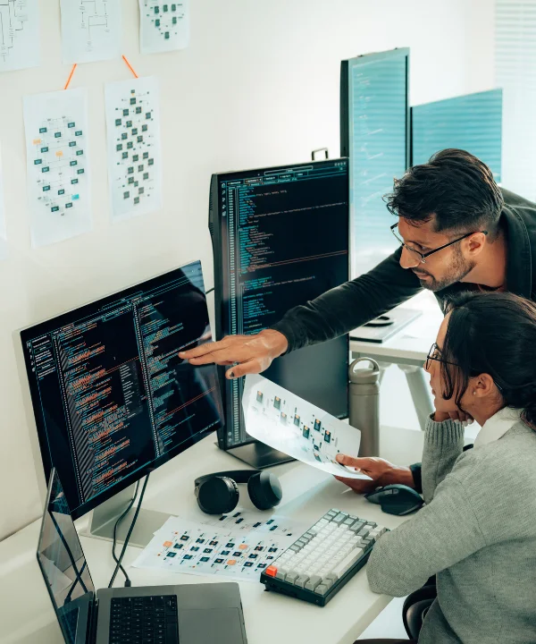 Zwei Personen arbeiten gemeinsam an Computern in einem modernen Büro.