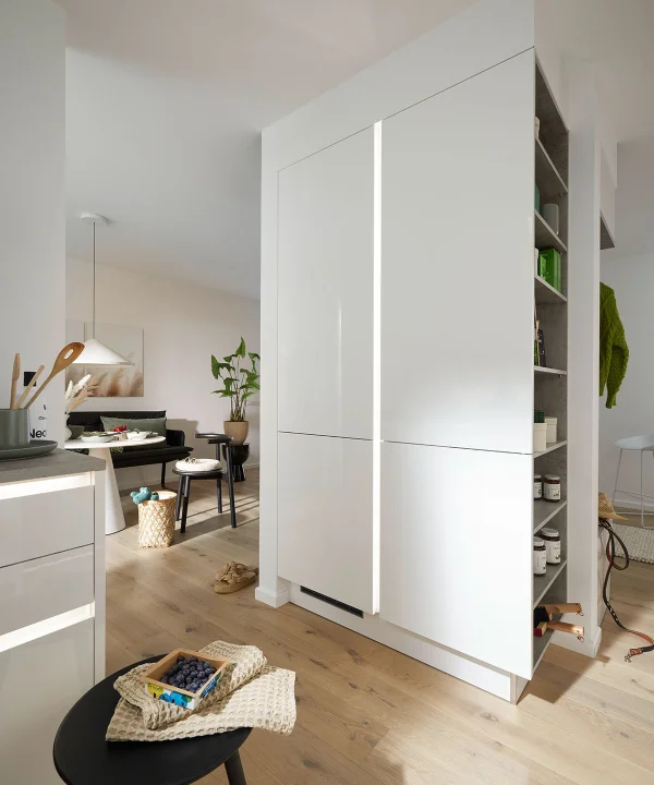 Eine moderne weiße Küche mit Holzfußboden und Pflanzen im Hintergrund, Nolte Küchen.