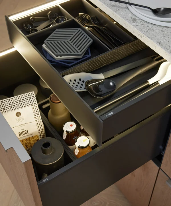 Eine geöffnete Küchenschublade mit Besteck und Gewürzen in einer modernen Nolte Küchen Umgebung.