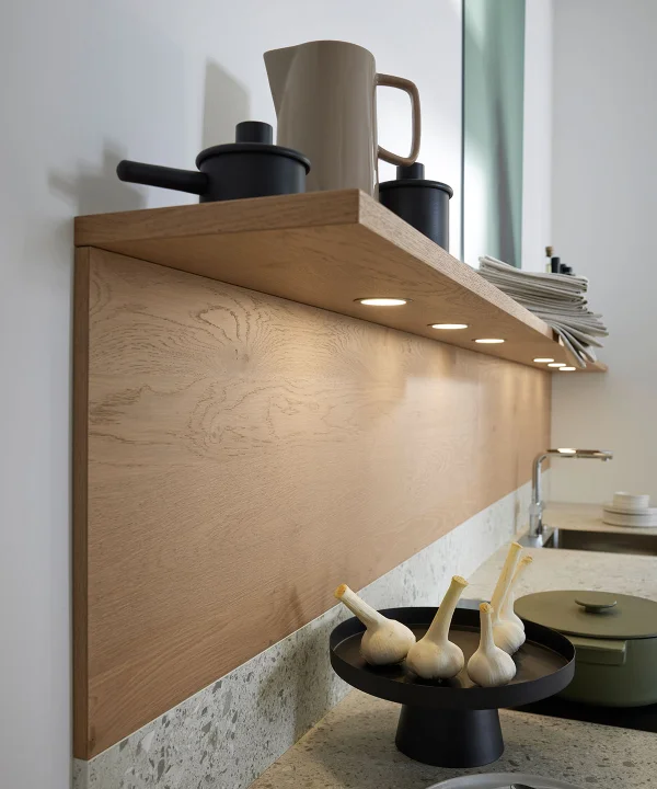 Ein Küchenregal mit Geschirr und Deko, darunter beleuchtete Arbeitsfläche. Nolte Küchen.